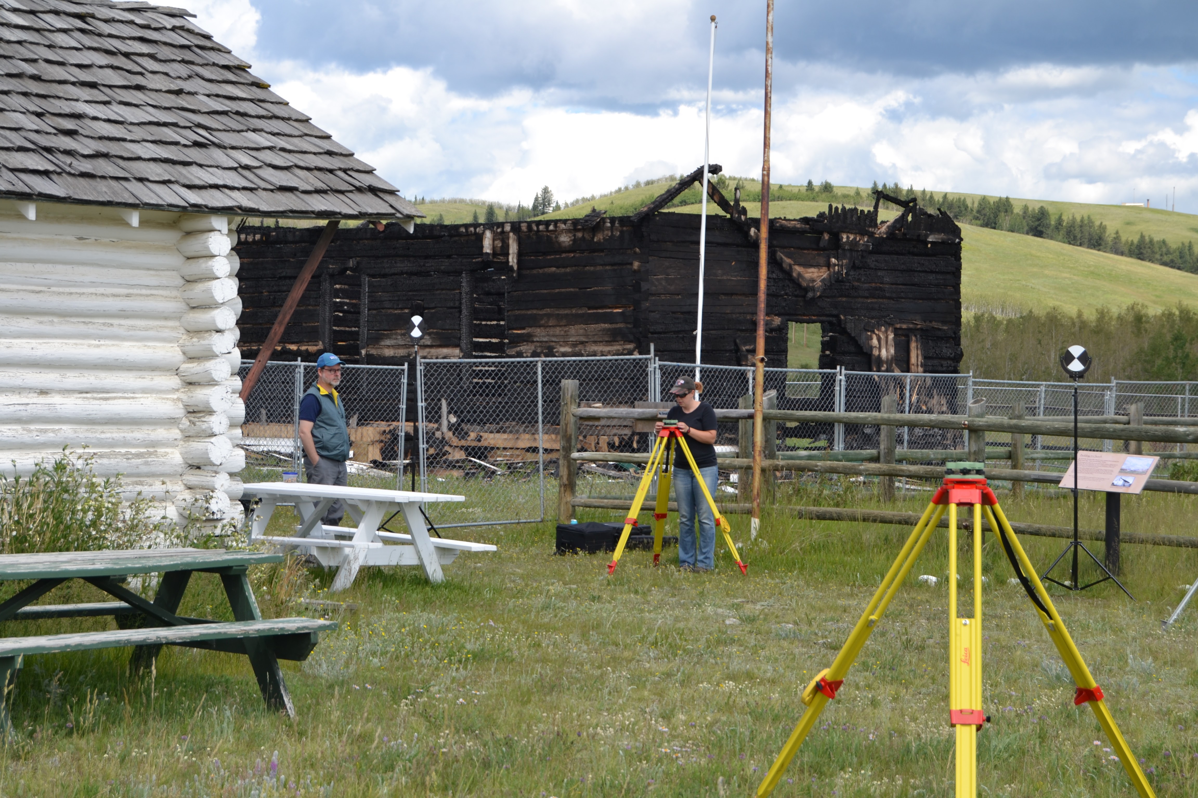 Dr. Peter Dawson and Christina Robinson setting up for terrestrial laser scanning at Walking Buffalo's cabin with the burnt remains of McDougall United Memorial Church in the background, June 24th, 2017.