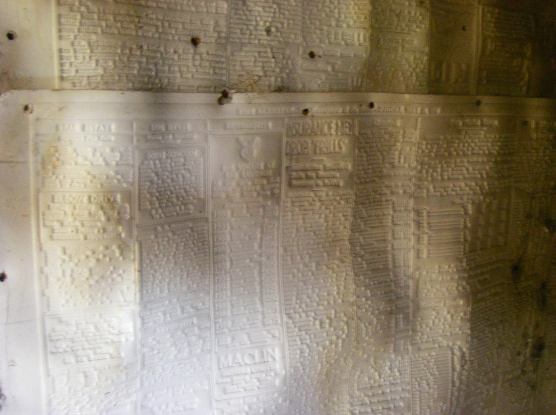 Internal wall covering of the western building next to the Springbank Hill wind-pump building. The wall covering appears to be vellum-like paper from the Albertan newspaper from around the 1940s.