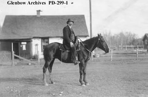 George Lane in front of ranch office/post office at Bar U Ranch, Pekisko, Alberta, 1916, by Fred Andrews.